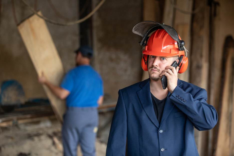 Man on phone at construction job - Overtime Violations